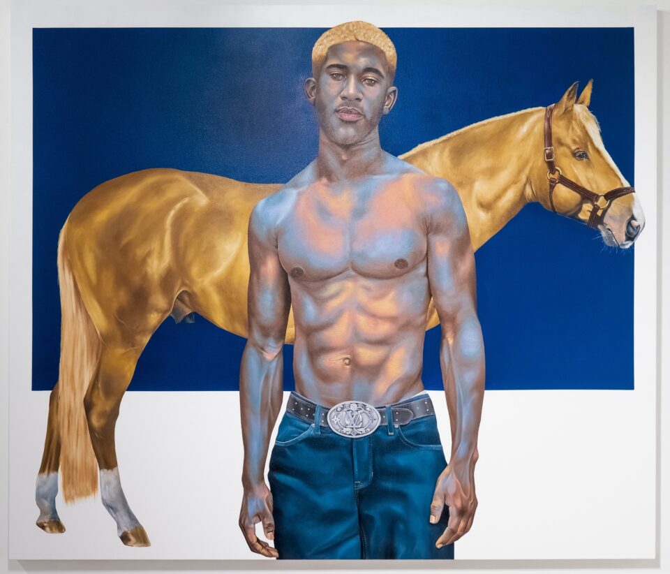 a portrait of a Black man wearing jeans and no shirt, standing in front of a tan-colored horse and gazing directly at the viewer