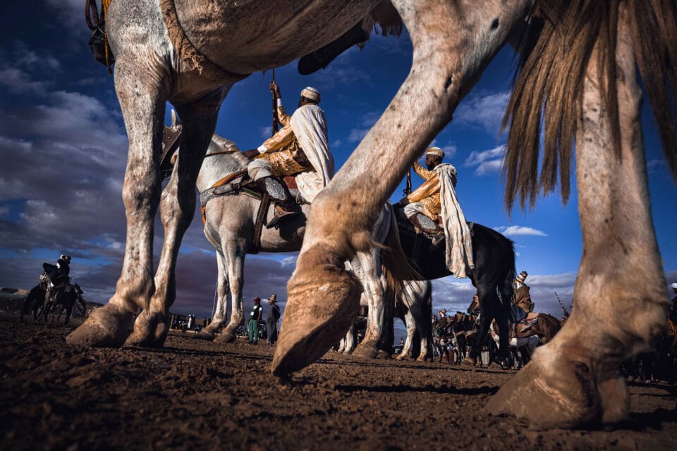 men on horseback ready for a competitive game, with the angle of the camera set down low to emphasize the horses' hooves