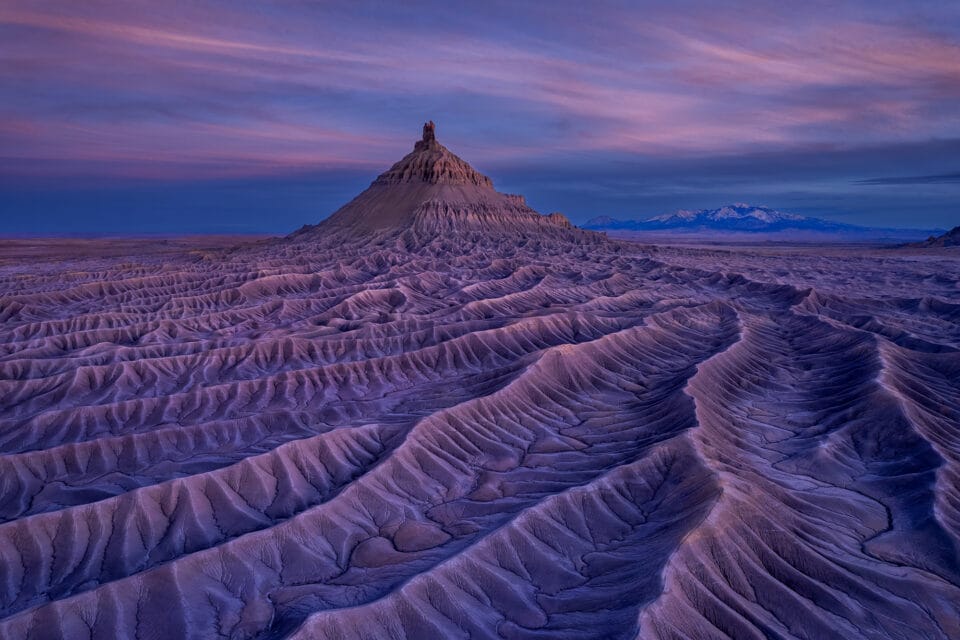 an aerial view of a dramatic geological formation in the Utah desert of a butte and numerous raised striations in the rock
