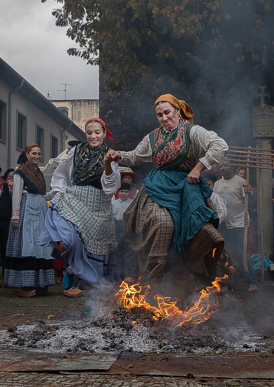 women jump over a fire in Portugal in celebration of the Feast of St. Martin