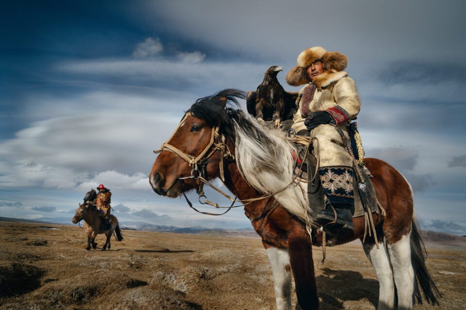 a hunter on horseback in the Mongolian landscape, holding a golden eagle
