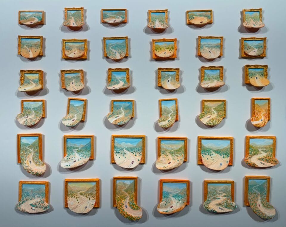a grid of miniature paintings, each depicting a landscape spilling out of the ornate frame with a tiny car driving on a winding dirt road