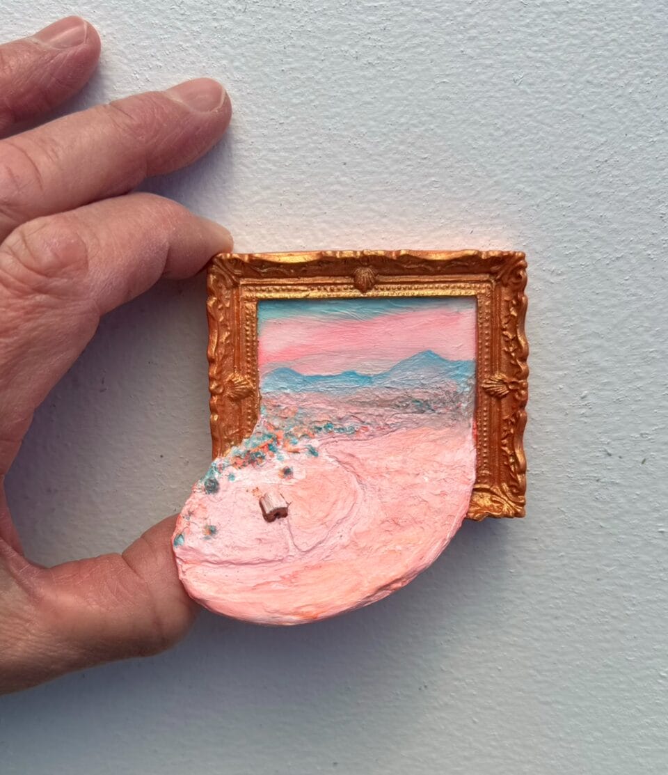 a miniature painting depicting a landscape spilling out of the ornate frame