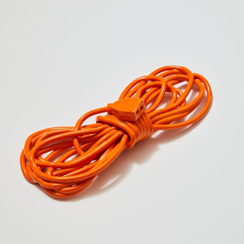 a ceramic sculpture of an orange power cord wound up around itself