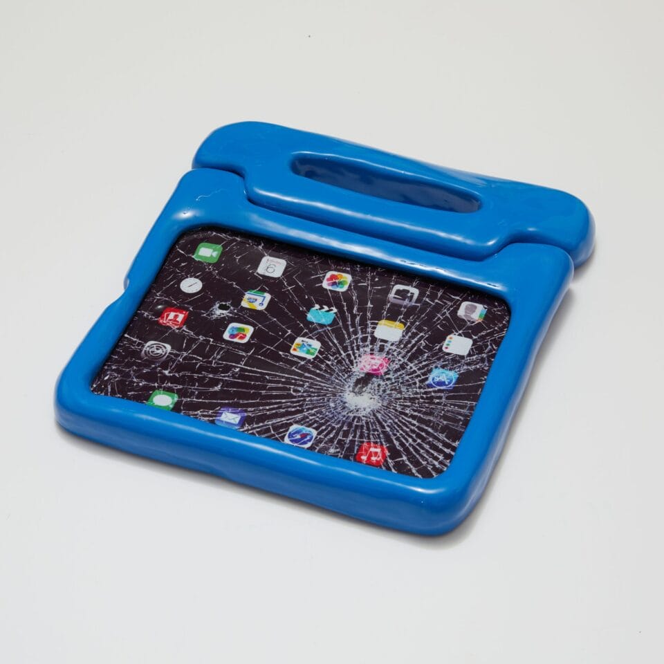a ceramic sculpture of an ipad with a blue children's case and a shattered screen