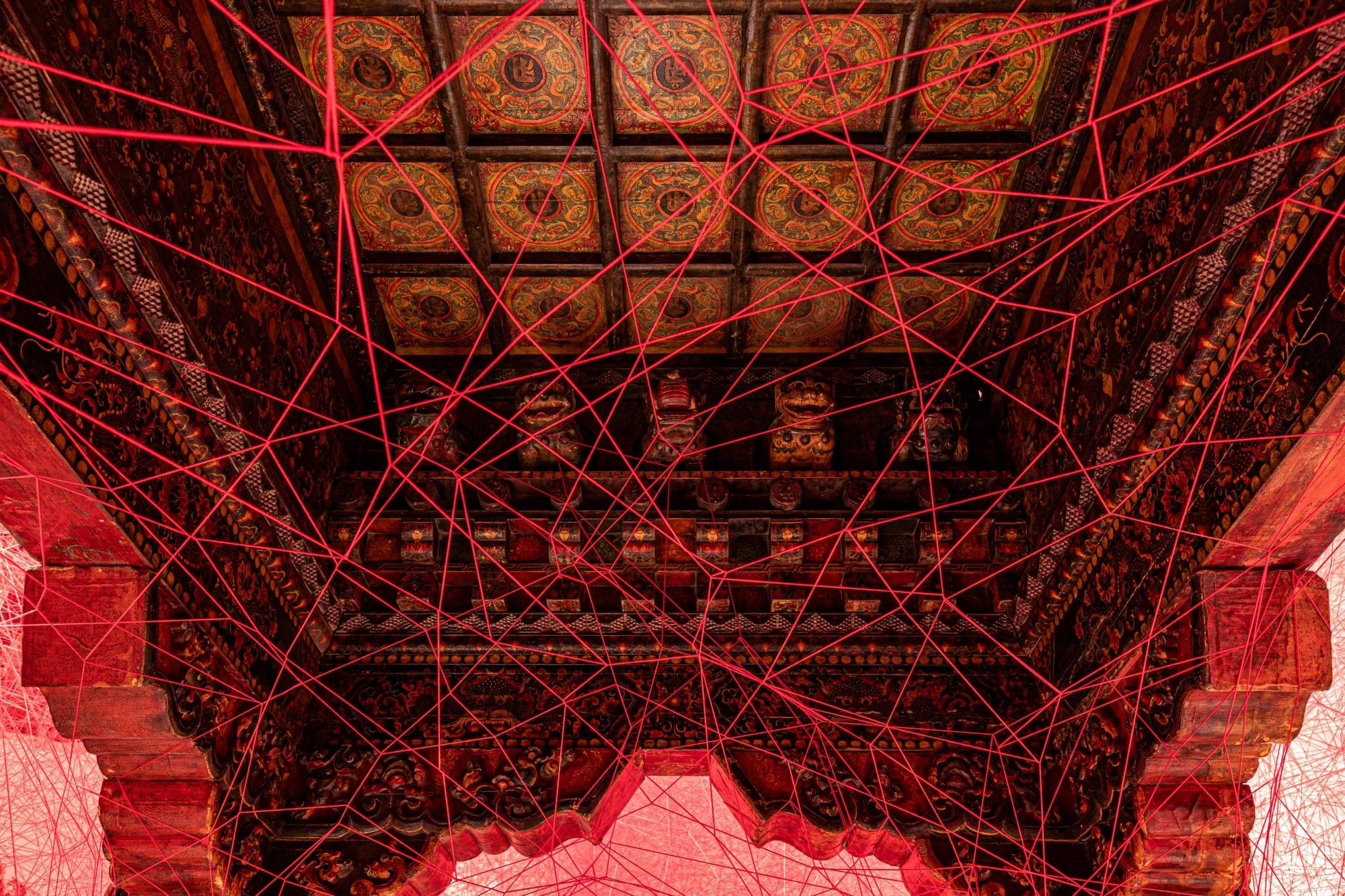 red string crisscrosses to wrap an elaborately carved structure