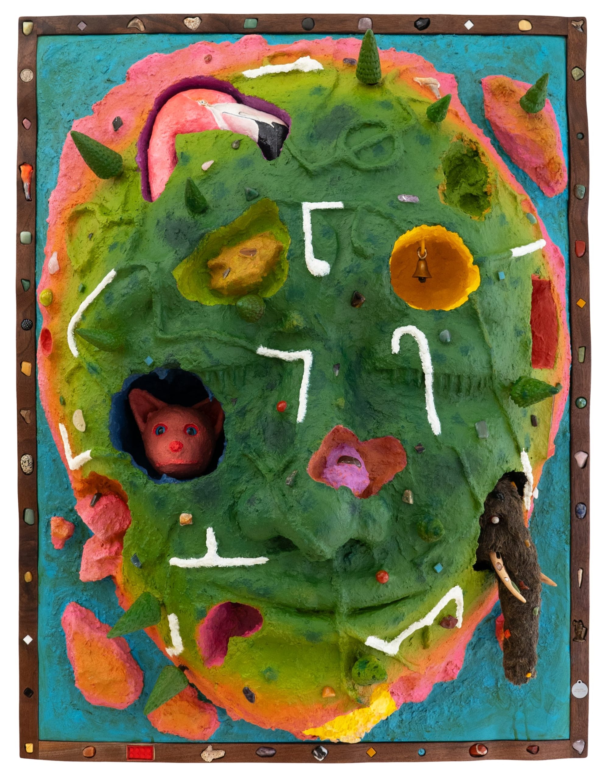 a wooly mammoth, pink animal, bell, and other objects embedded into a sculptural painting shaped like a face