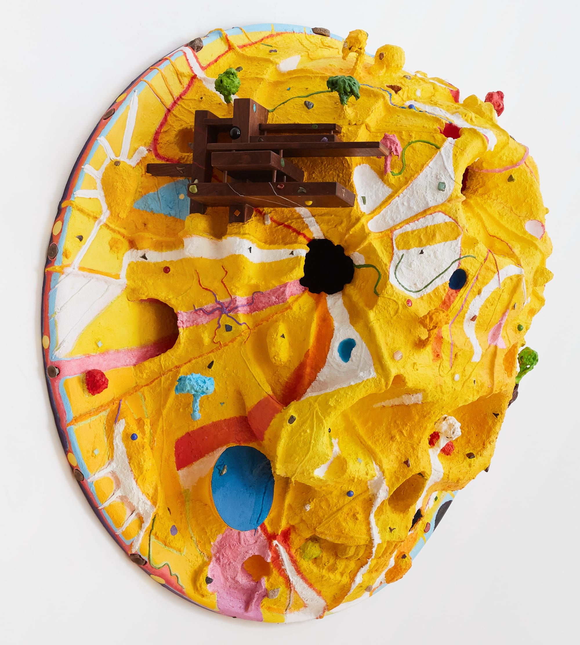a yellow sculpture painting with wood, stone, and other objects embedded within it