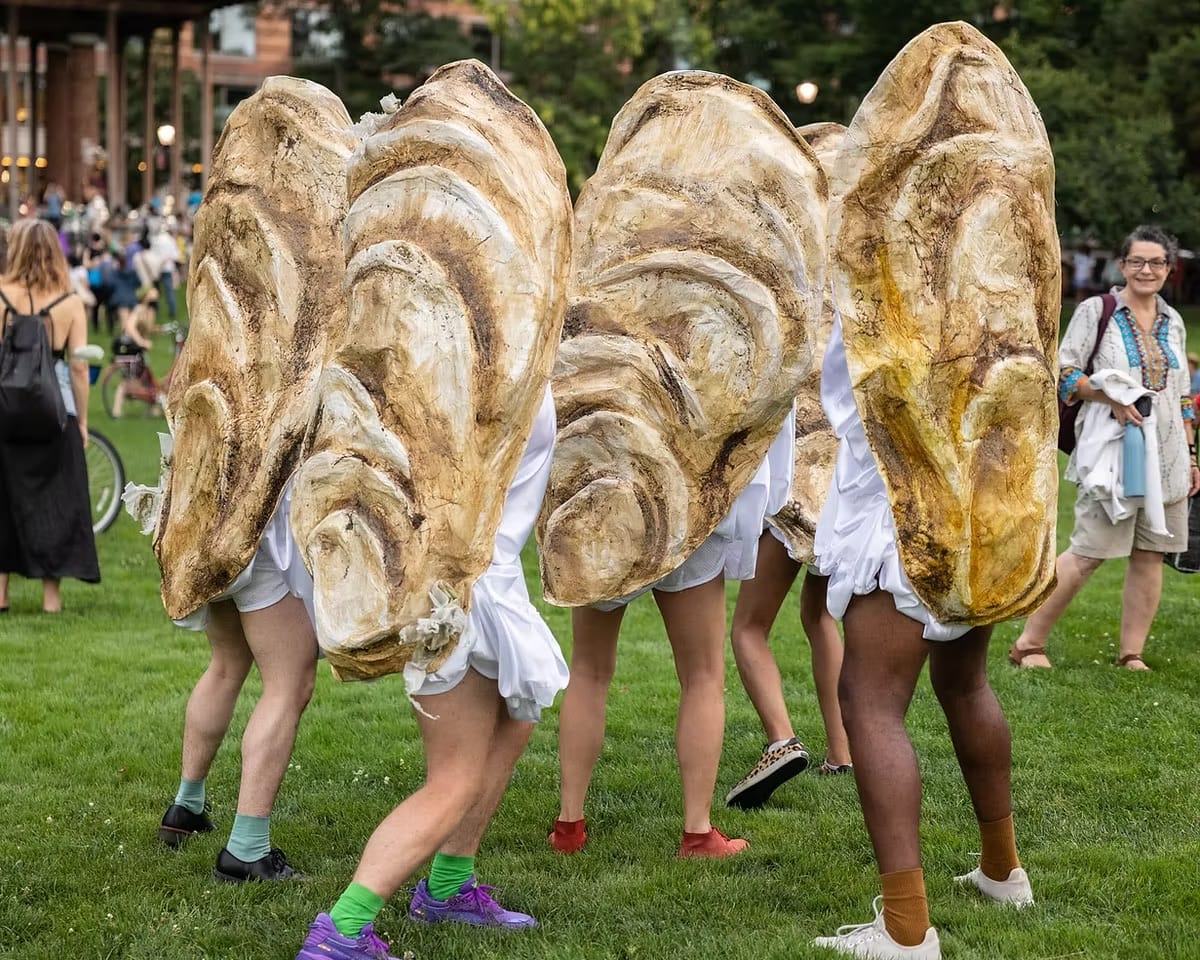 a group of people perform an art piece, dressed like oysters