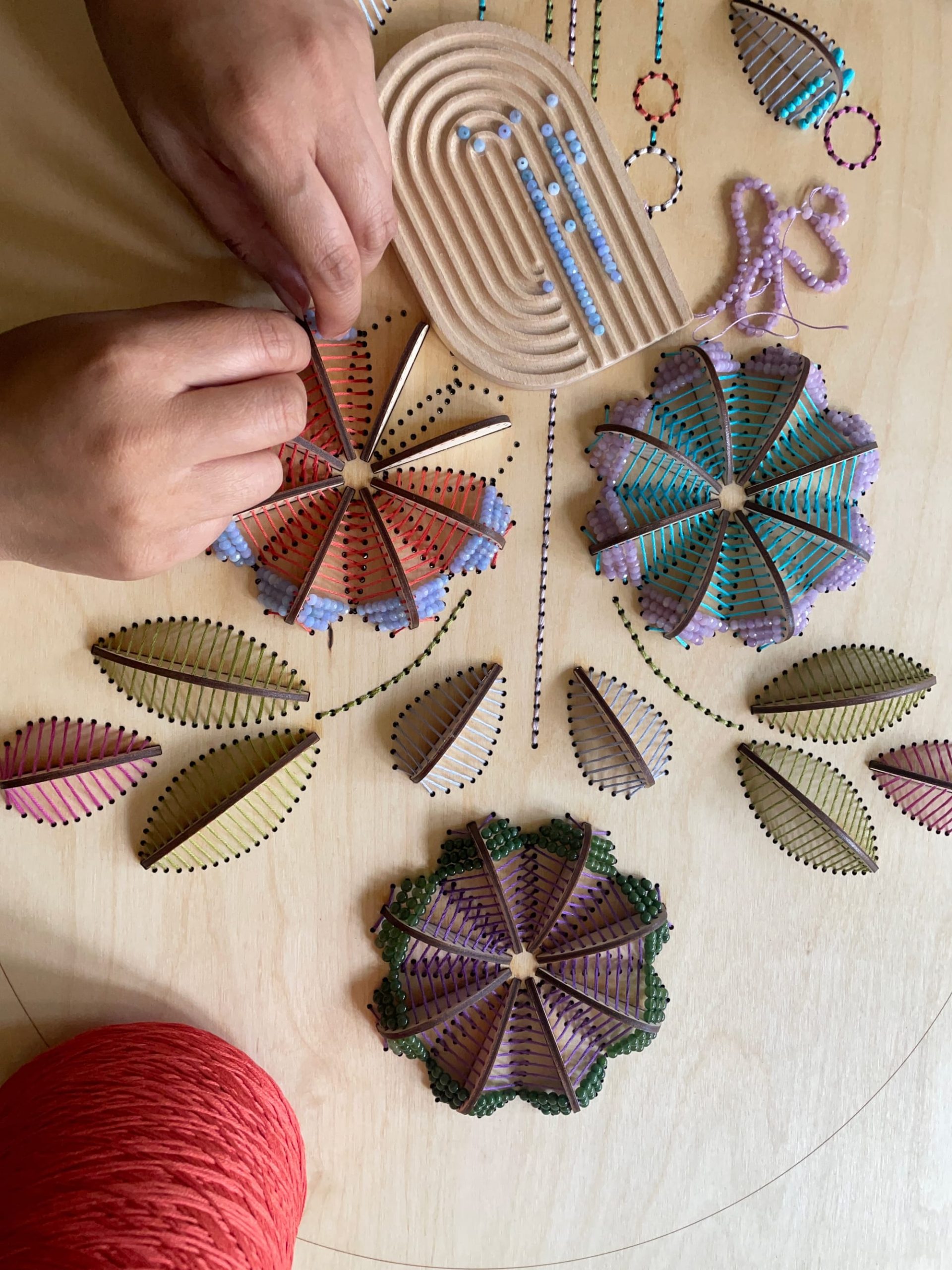 hands working on a sculptural floral embroidery on wood