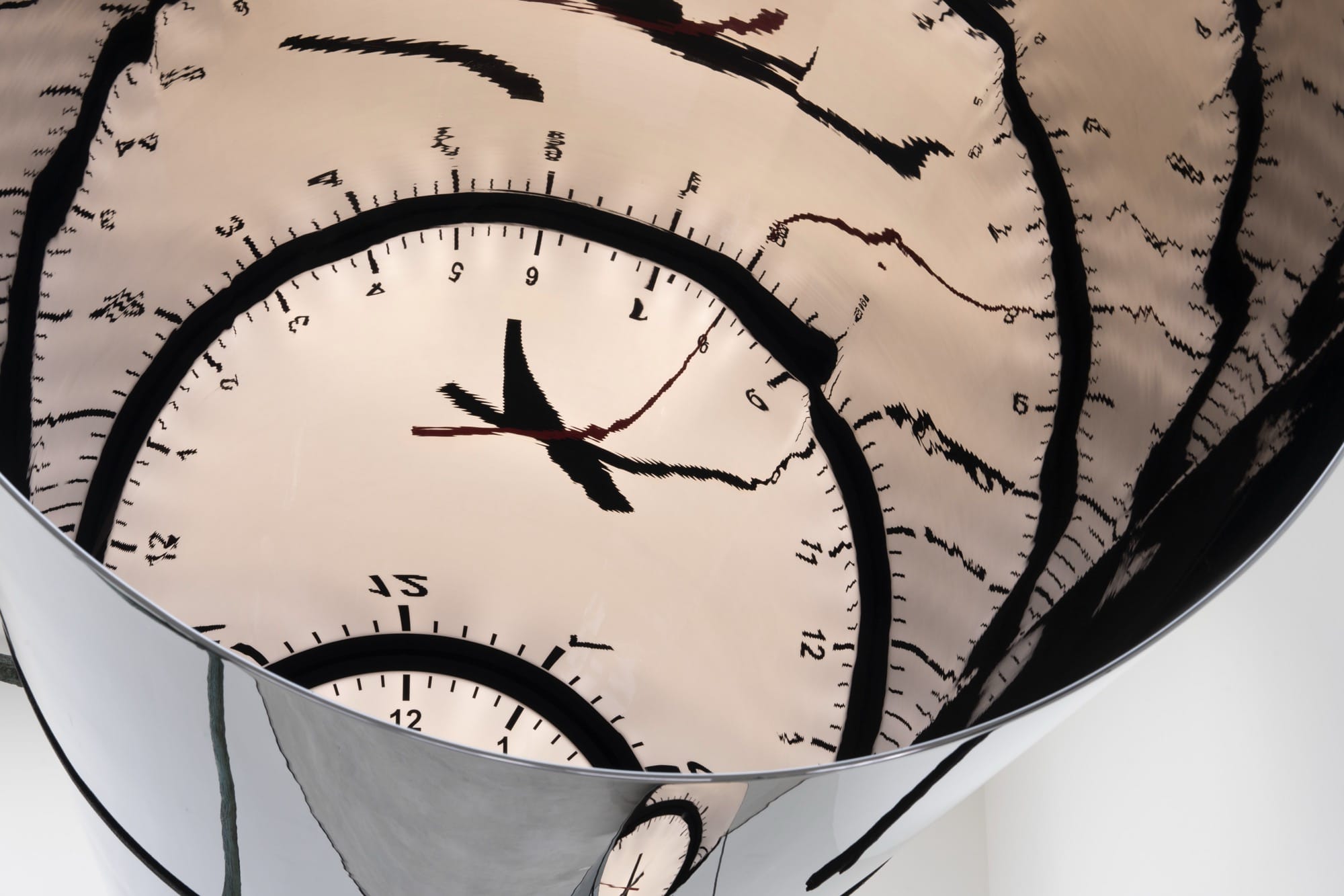 a detail image a large suspended cylindrical metal sculpture with a distorted clock on the end