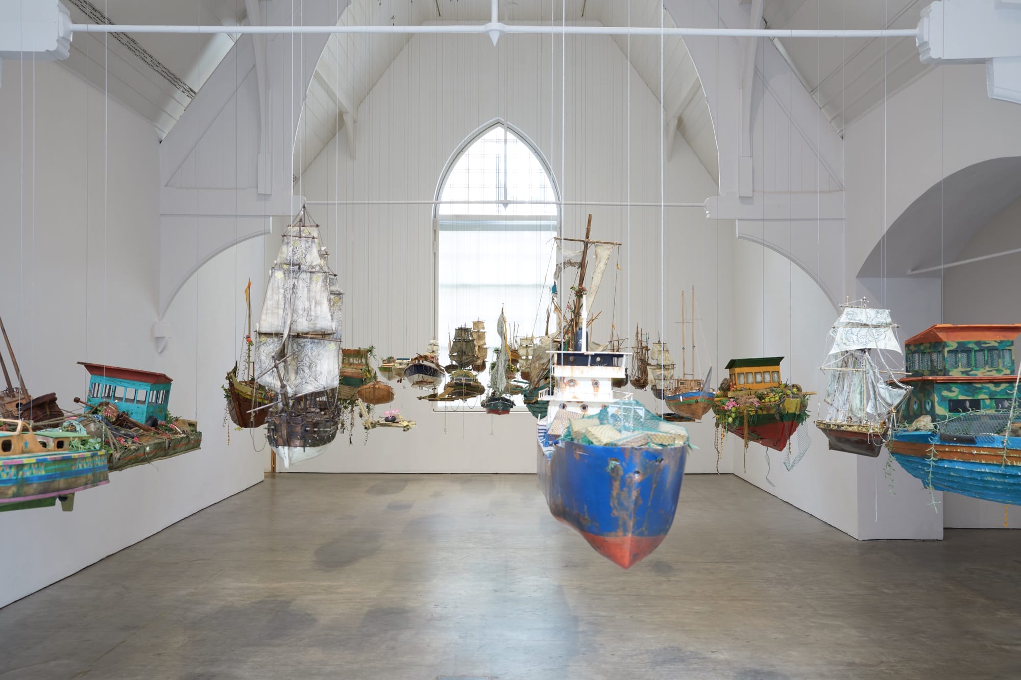 a collection of boats hangs in a gallery