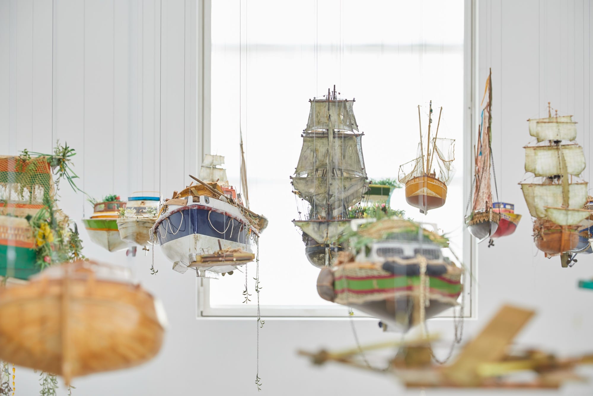 a collection of boats hangs in a gallery