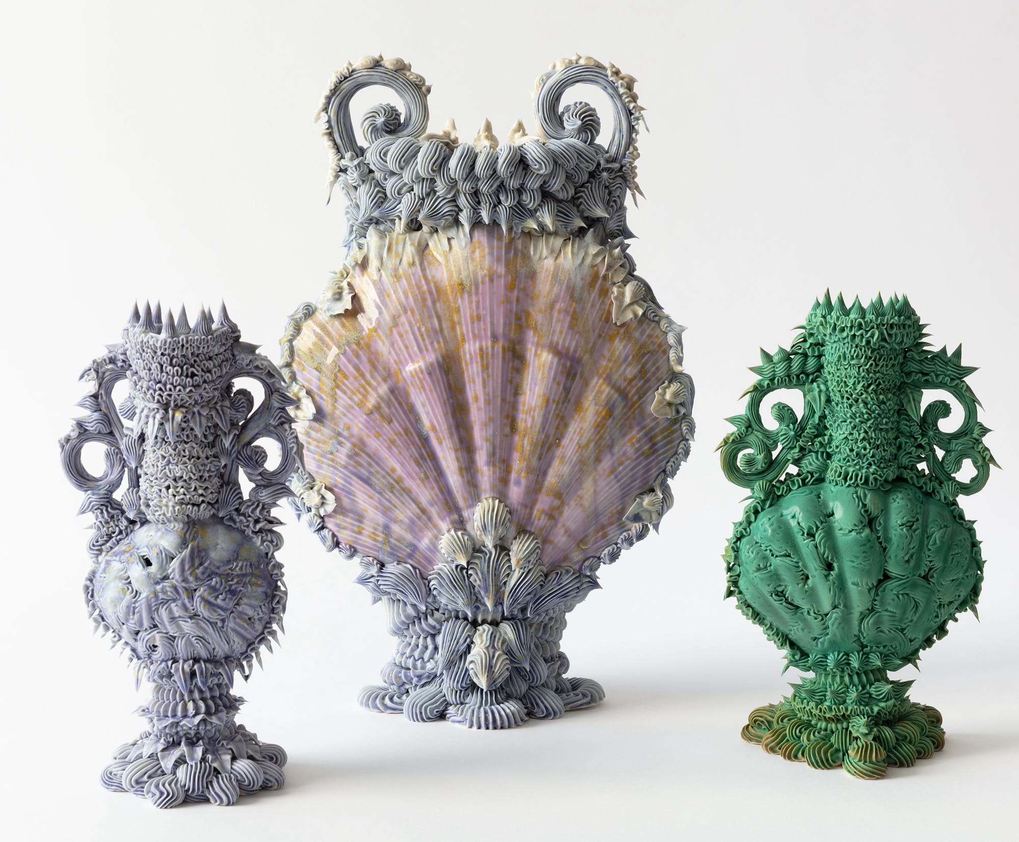 a series of three elaborate, multi-colored ceramic vases made with clay piped like frosting
