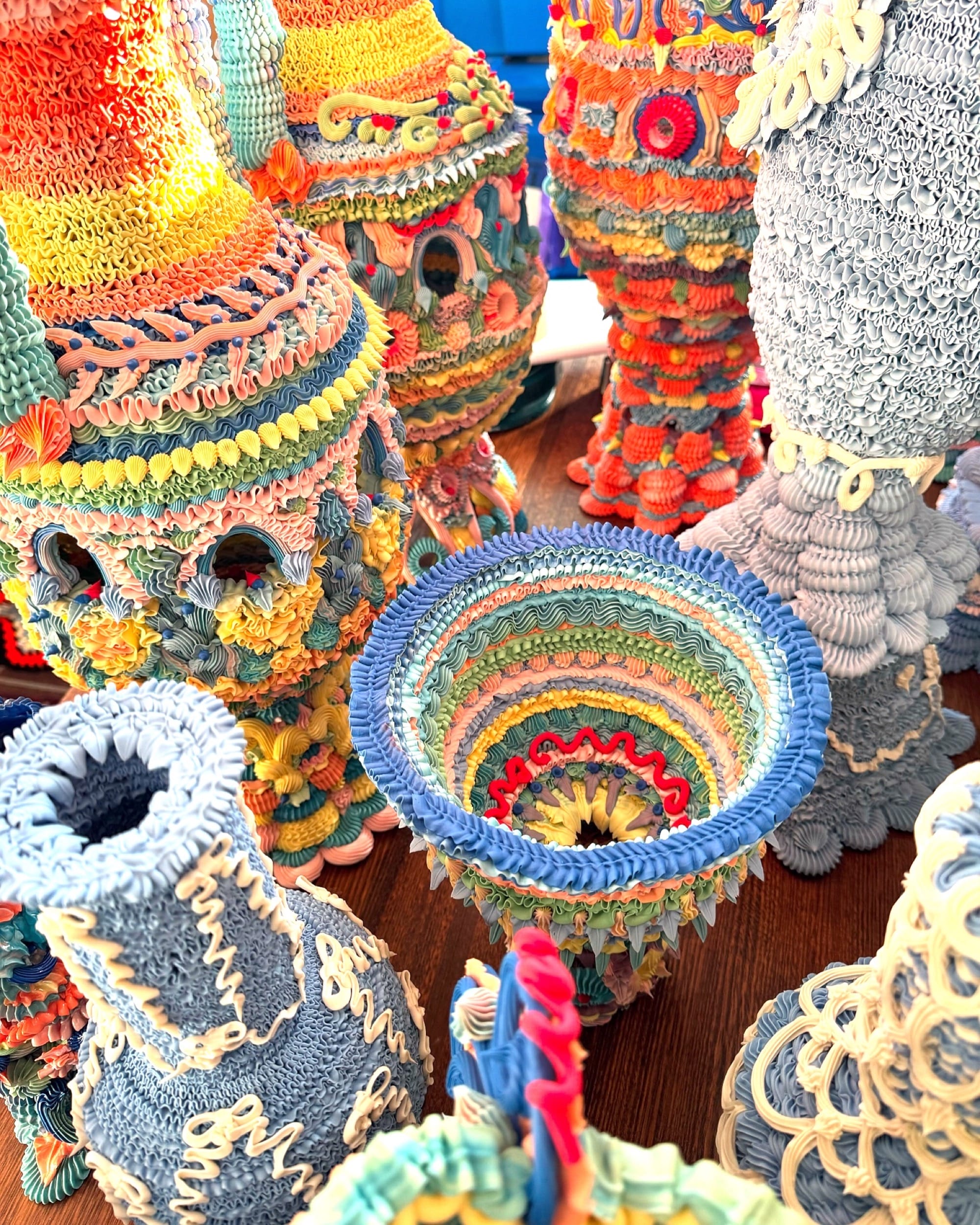 a series of elaborate, multi-colored ceramic vases made with clay piped like frosting, viewed from above