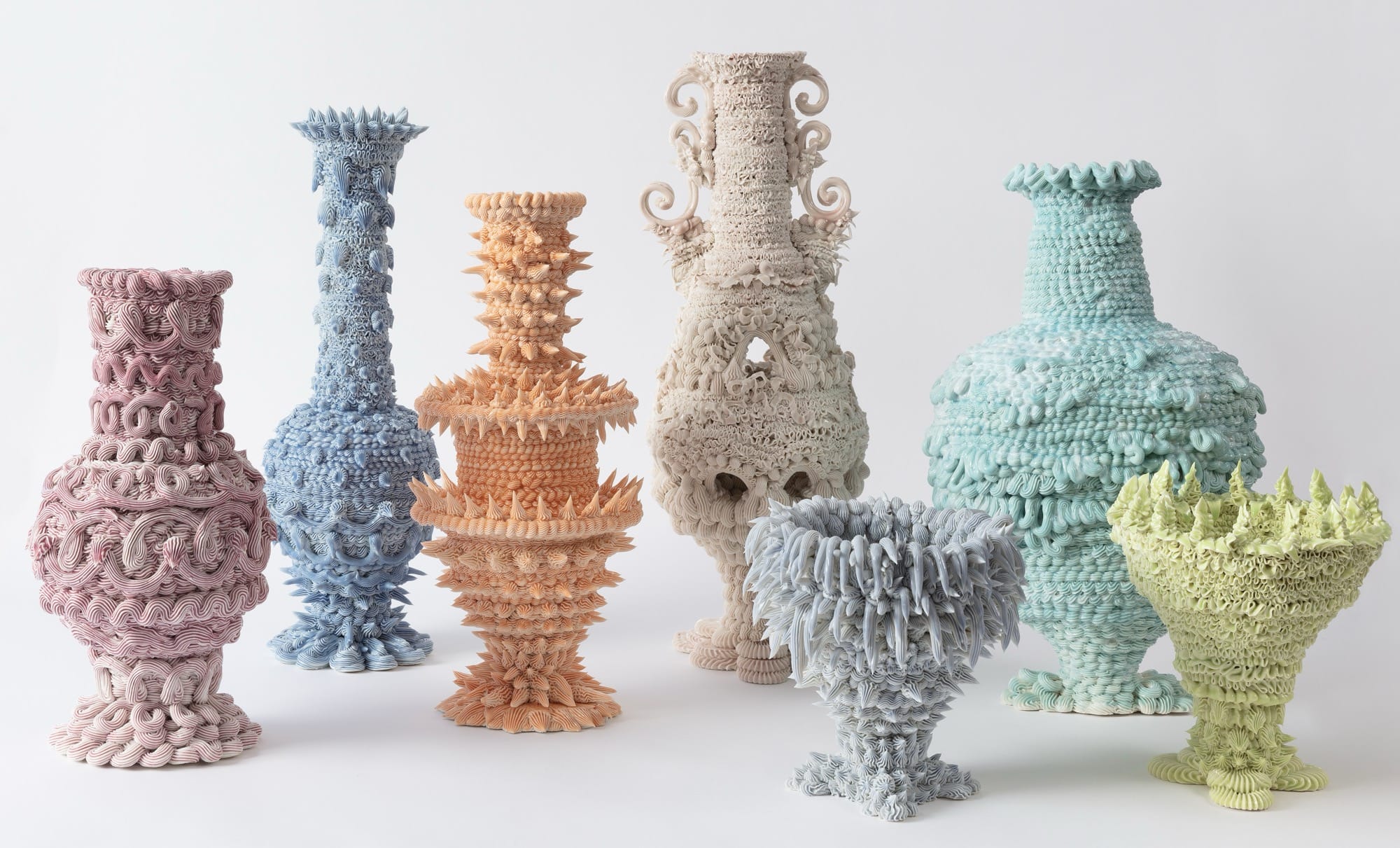 a series of seven elaborate, pastel-colored ceramic vases made with clay piped like frosting