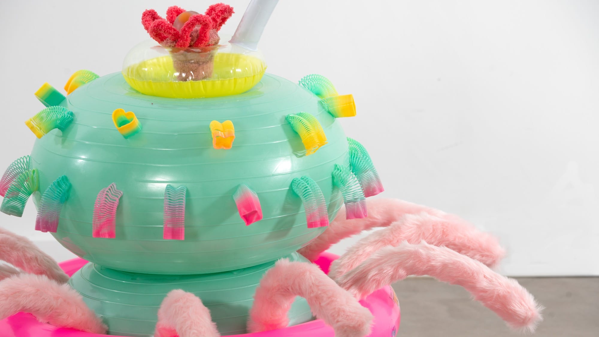 a detail of an abstract inflatable artwork that resembles a pink and green, alien-like creature