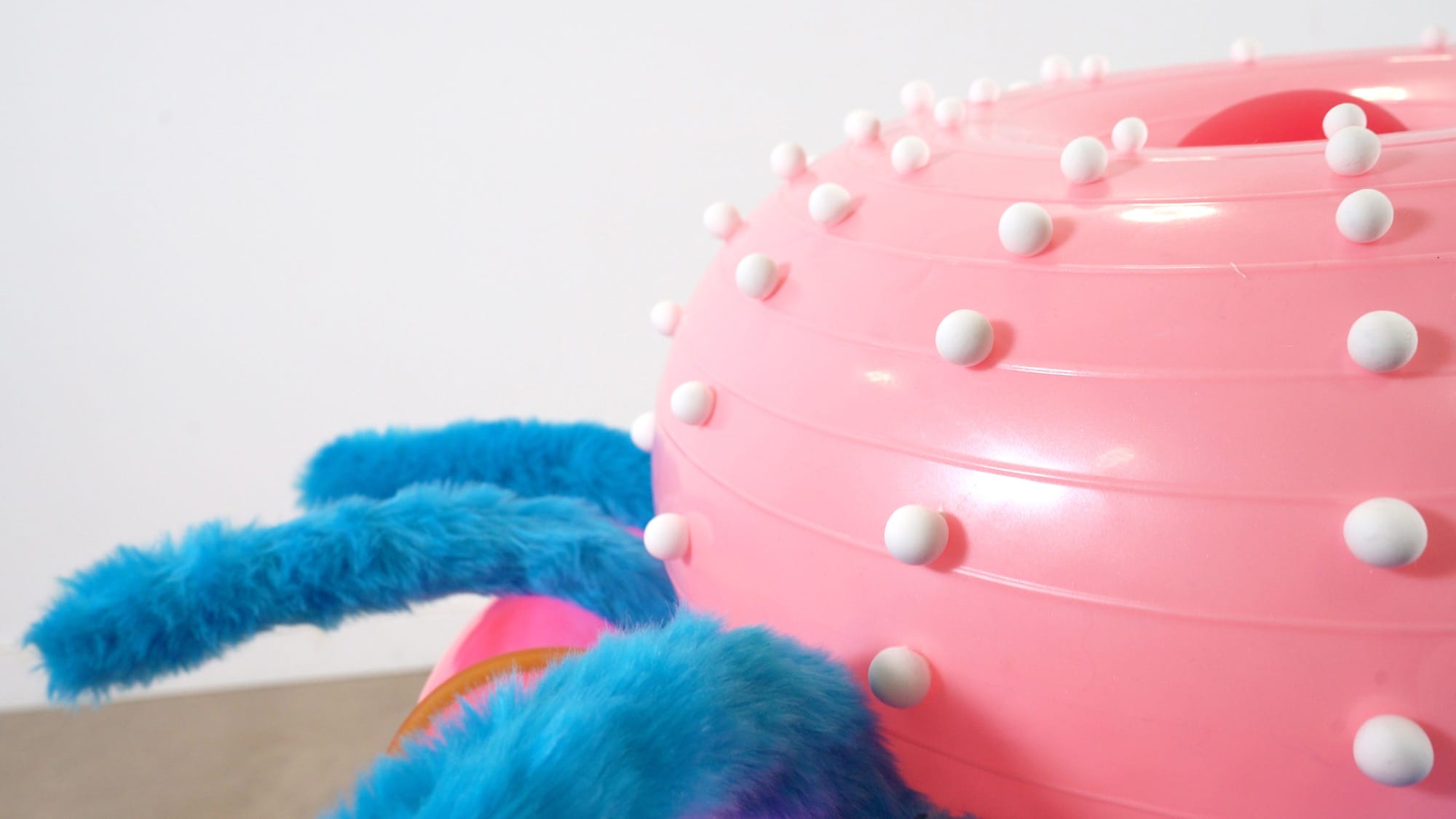a detail of an abstract inflatable artwork that resembles a pink and blue, alien-like creature
