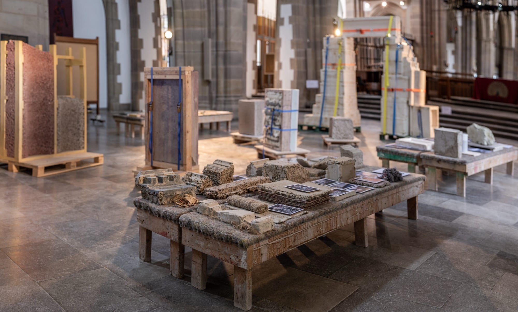 a detail of a sculptural installation with numerous plaster and stone objects on tables and pedestals