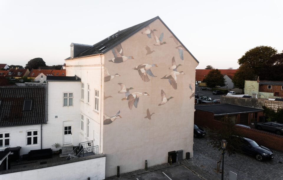 a mural on the side of a house depicting birds flying