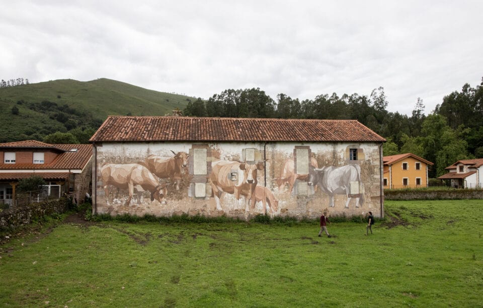 a mural of cows and donkeys on the side of an old hospital building